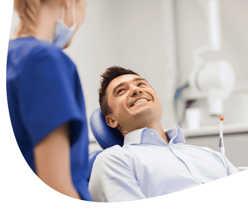 Mężczyzna na fotelu dentystycznym uśmiecha się do dentysty