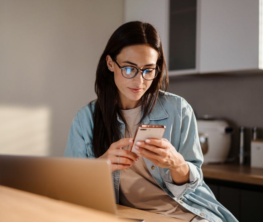 Kobieta przy biurku wpatrzona w telefon