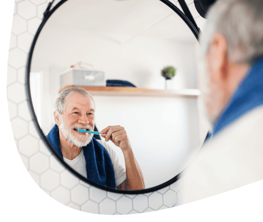 Starszy mężczyzna myje zęby przed lustrem