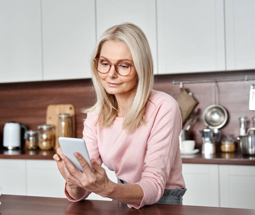 Kobieta przeglądająca telefon w kuchni