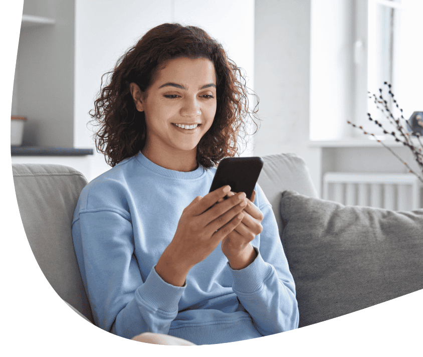 Kobieta uśmiechnięta wpatrzona w telefon