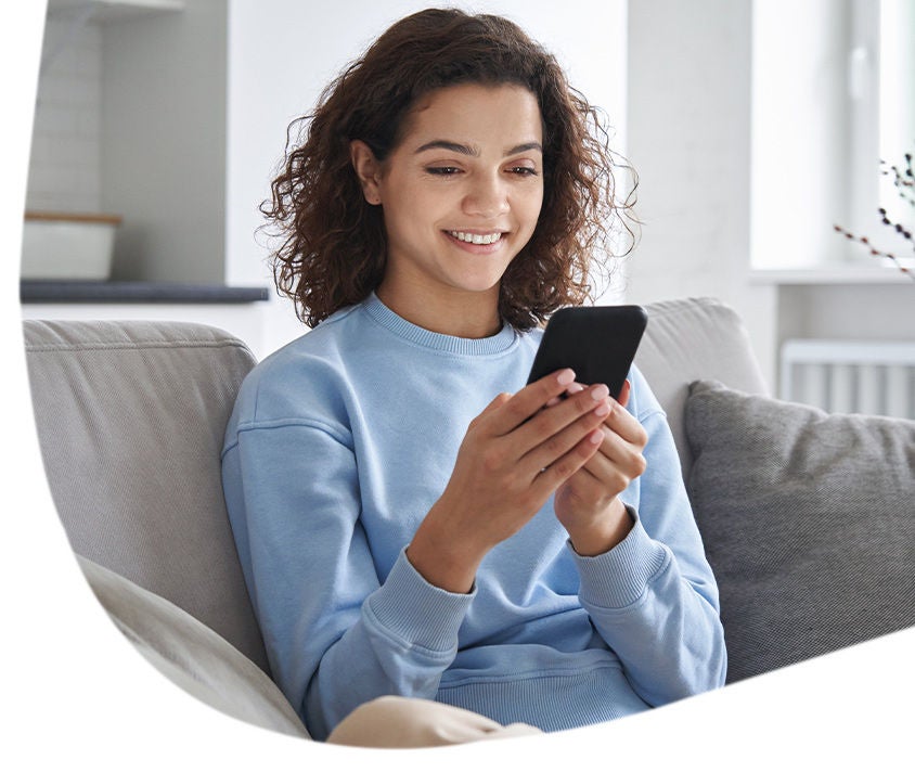 Kobieta uśmiechnięta wpatrzona w telefon