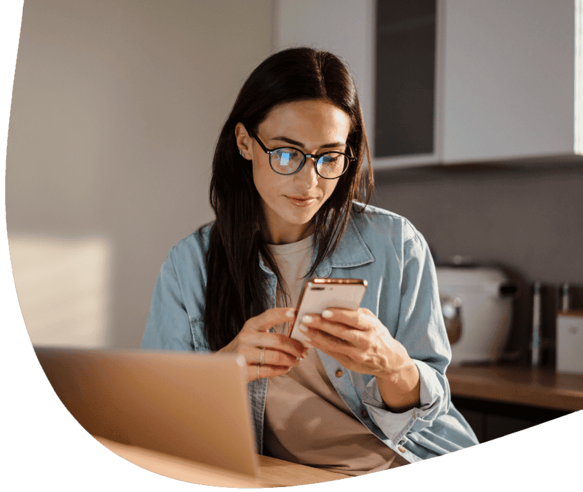 Kobieta przy biurku wpatrzona w telefon